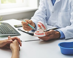 Dentist pointing to model of teeth in office