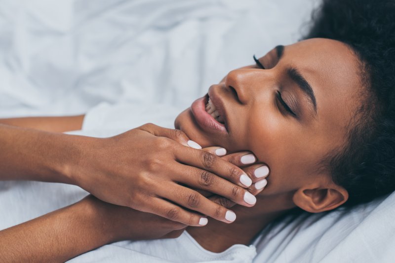 a woman holding her jaw while in bed