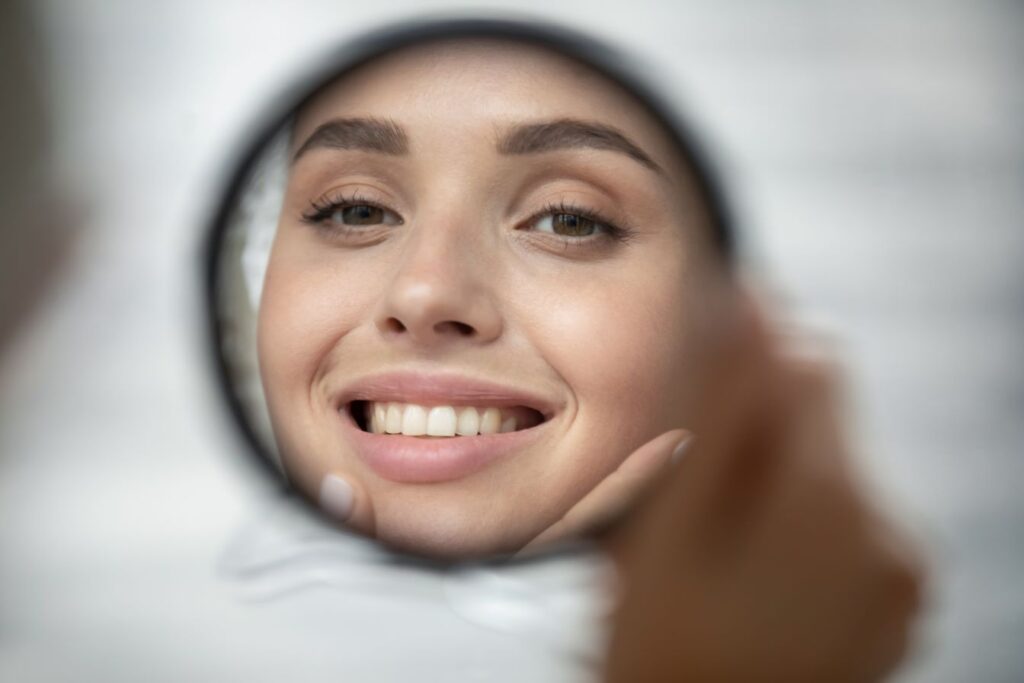 A woman looking at her smile in the mirror